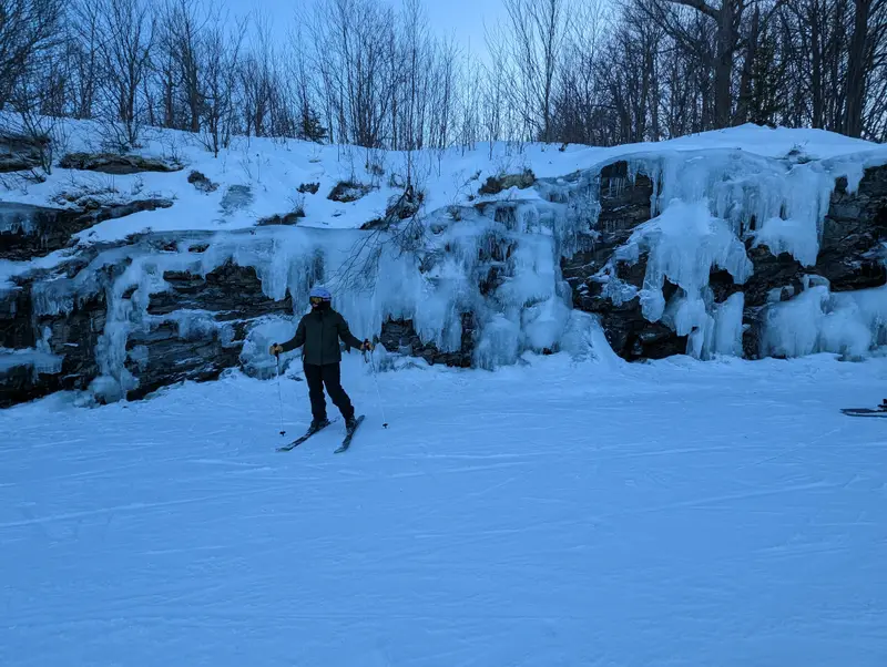 Cross-country skier passing frozen ice cliffs